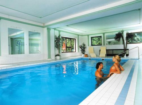 Ein Mann und eine Frau, die im Schwimmbad sitzen in der Unterkunft Das Steinberger in Altlengbach