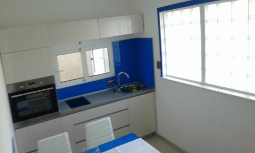 a kitchen with blue and white cabinets and a window at Mali Šjor in Primošten