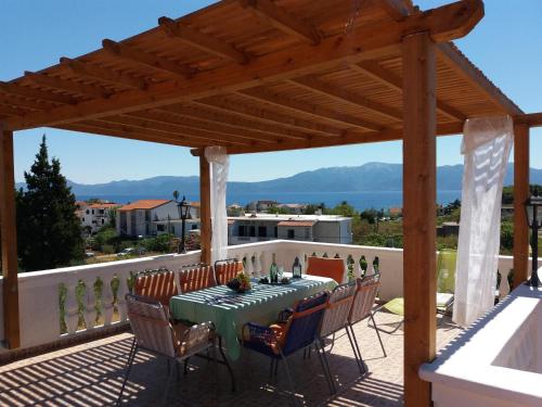 a wooden pergola with a table and chairs on a patio at Apartments Piacun in Sućuraj