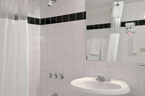 Baño blanco con lavabo y espejo en Thunderbird Beach Hotel, en Miami Beach