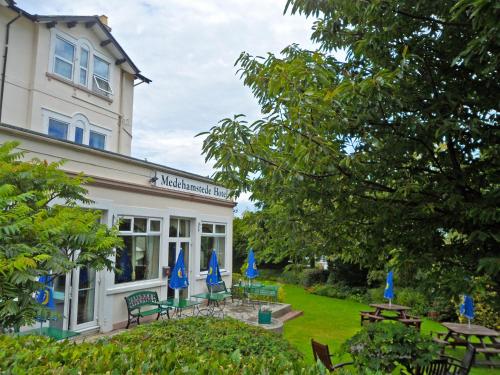 a building with blue umbrellas in a yard at Medehamstede Hotel in Shanklin