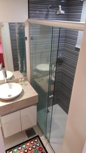 a bathroom with a glass shower and a sink at Apart-Hotel in Goiânia