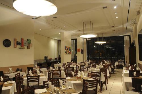 un comedor con mesas, sillas y luces en Apart-Hotel, en Goiânia