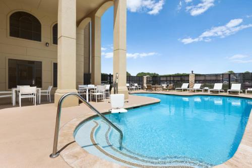 a pool at a hotel with chairs and tables at Country Inn & Suites by Radisson, Houston Northwest, TX in Houston