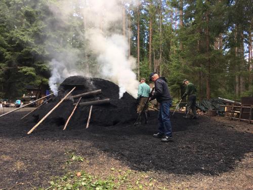 a group of people standing around a fire pit at STF Kolarbyn Eco-Lodge in Skinnskatteberg