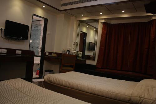 a bedroom with two beds and a desk and a mirror at Hotel Karl Residency in Mumbai