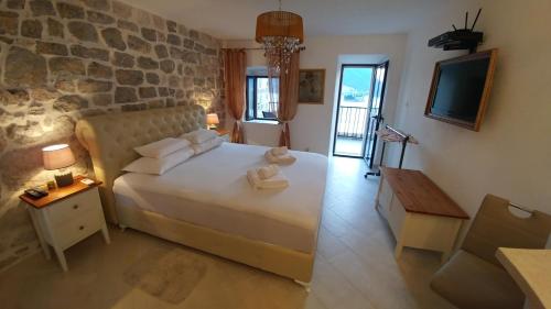 sypialnia z dużym łóżkiem i kamienną ścianą w obiekcie Bella Vista Zmukic w mieście Perast