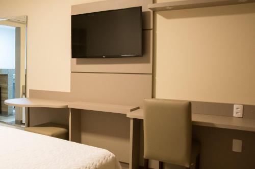 a room with a bed and a desk with a tv at Paracambi Top Hotel in Paracambi