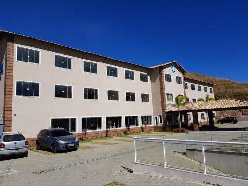 a large white building with cars parked in a parking lot at Paracambi Top Hotel in Paracambi