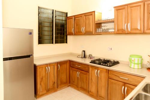 a kitchen with wooden cabinets and a stainless steel refrigerator at Connect Africa Apartments in Accra