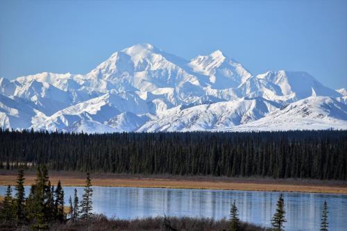 a snow covered mountain range with a lake and trees at Backwoods Lodge in Cantwell