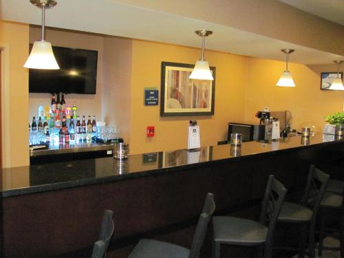 a bar in a restaurant with chairs and lights at Cobblestone Inn & Suites - Ambridge in Ambridge
