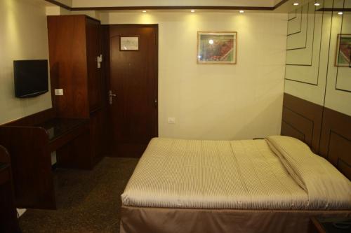 a small room with a bed and a desk and a television at Hotel Karl Residency in Mumbai