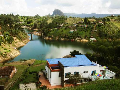 a house with a blue roof next to a river at Hotel Familiar El Remanso Del Agua in Guatapé