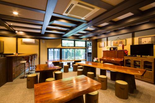una grande stanza con tavoli e sgabelli in legno di Matsubaya Ryokan a Kyoto