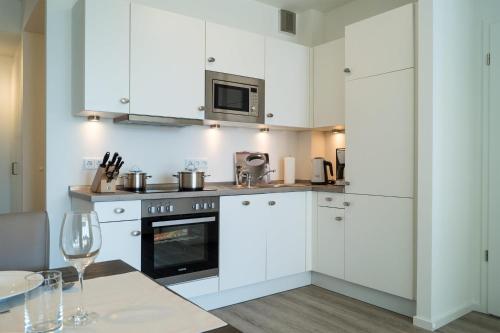 a kitchen with white cabinets and a table at Südkap D-08 in Pelzerhaken