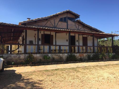 a house with a porch and a fence at Pousada São Gonçalo in São Gonçalo do Rio das Pedras