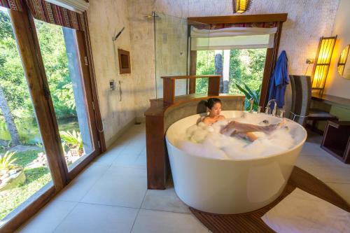 a man sitting in a bath tub in a room at Namkat Yorla Pa Resort in Ban Kat