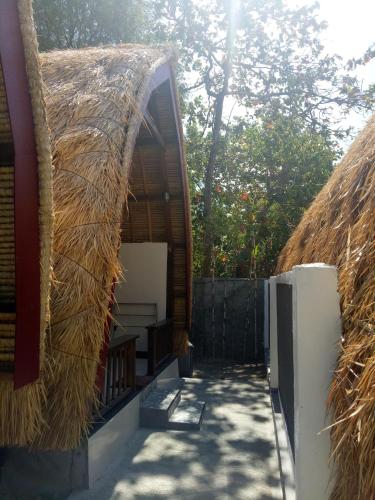 a building with a thatched roof with a pathway at Krisna Bungalows and Restaurant in Sekotong