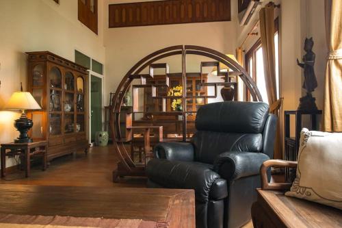 sala de estar con sofá de cuero y silla en Artisan's Antique House - Silom en Bangkok