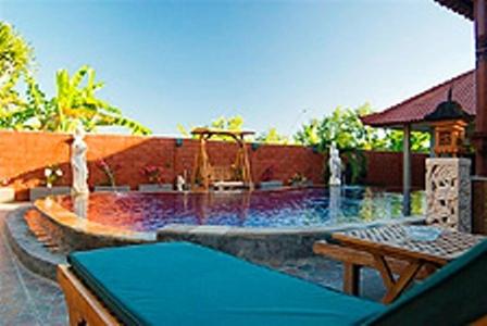 a large swimming pool with a table and a bench at Meriki Apartment in Seminyak