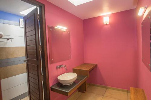ein Badezimmer mit einer rosa Wand mit einem Waschbecken und einer Toilette in der Unterkunft Century Village Resort in Mananthavady