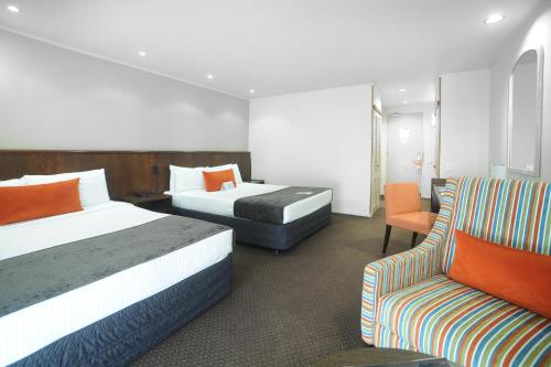 a hotel room with two beds and a chair at Quality Hotel Lincoln Green in Auckland