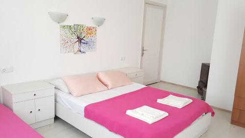 Schlafzimmer mit einem Bett mit rosa und weißer Bettwäsche in der Unterkunft Ayvalık Pansiyon in Ayvalık