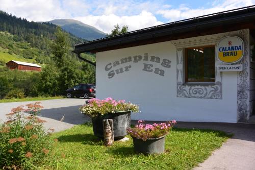 a building with two buckets of flowers outside of it at Camping Sur En in Sent