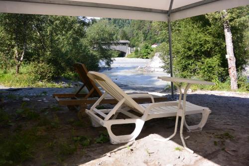 two chairs and a table under an umbrella next to a river at Camping Sur En in Sent
