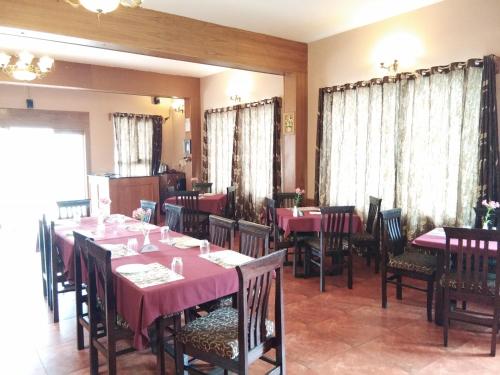 uma sala de jantar com mesas e cadeiras com toalhas de mesa cor-de-rosa em Berry Hills Resort em Ooty