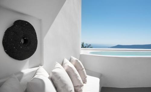 a room with white pillows and a view of the ocean at Native Eco Villas in Imerovigli