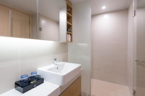 a white bathroom with a sink and a shower at Yumi Apartment Lida Plaza Branch in Guangzhou