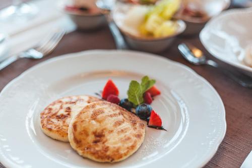 a white plate with pancakes and fruit on a table at Boutique Hotel Light House Jurmala in Jūrmala