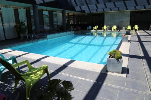 uma piscina com uma cadeira verde e cadeiras em Cors'Hotel em Biguglia