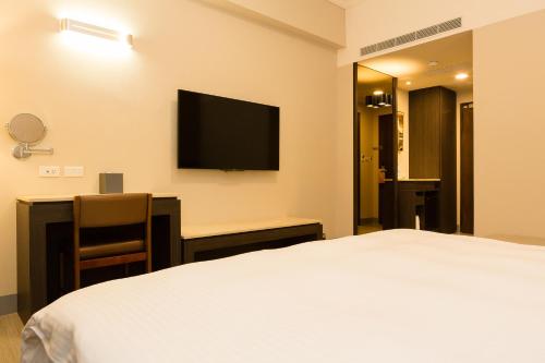 a hotel room with a bed and a desk and a television at V-Hotel in Taitung City