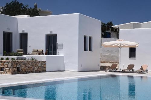 a white villa with a swimming pool and an umbrella at Ionathan Koufonisia Suites in Koufonisia