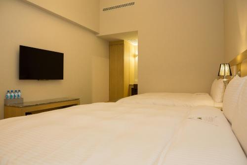 a hotel room with two beds and a flat screen tv at V-Hotel in Taitung City