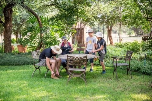 a group of people sitting around a table in the grass at Boubou Bed and Breakfast in Rustenburg