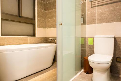 a bathroom with a toilet and a tub and a sink at V-Hotel in Taitung City