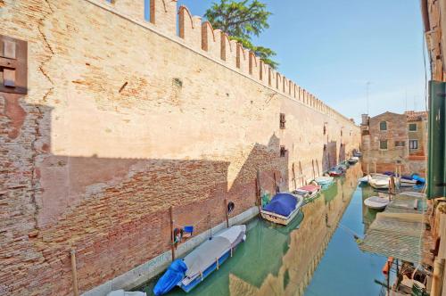 a group of boats in a canal next to a brick wall at DolceVita Apartments N 393 in Venice