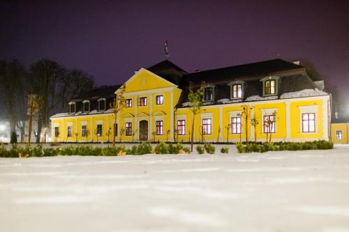 a yellow building in the snow at night at Forgách Kastély in Mándok