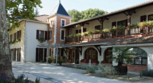 a building with a turret and flowers on the balconies at Relais de la Poste in Magescq