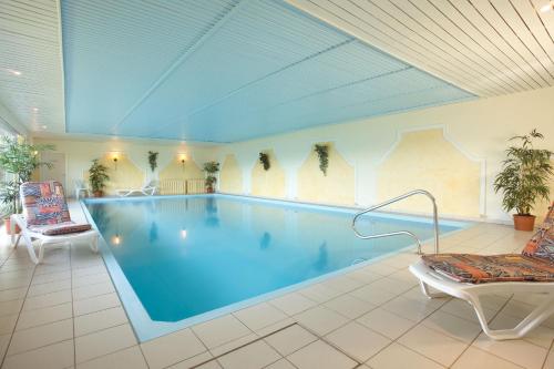 ein großer Pool in einem Zimmer mit Stühlen in der Unterkunft AKZENT Hotel Haus Sonnenberg in Schotten