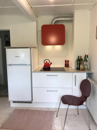 a kitchen with a white refrigerator and a red tea kettle at Apple Cottage in Vejby