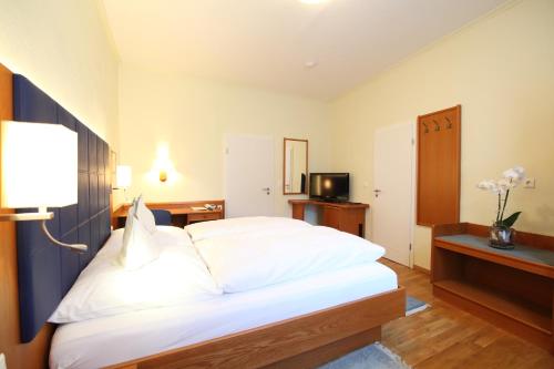 a bedroom with a large white bed and a television at Hotel Ickhorn in Werne an der Lippe