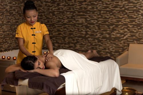 a woman is giving a man a massage on a bed at Feathers- A Radha Hotel, Chennai in Chennai