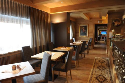a dining room with tables and chairs and a window at Hotel Italia in Castello di Fiemme