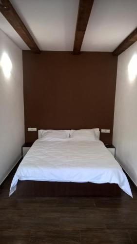 a bedroom with a white bed in a room at Casutele Andreica in Vişeu de Sus