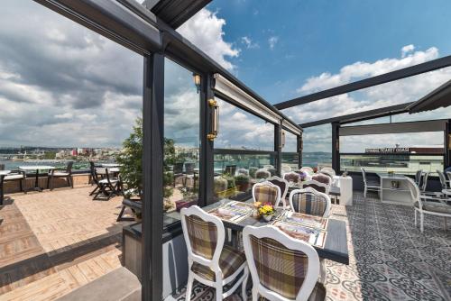 a patio with white chairs and tables and windows at Alpek Hotel in Istanbul